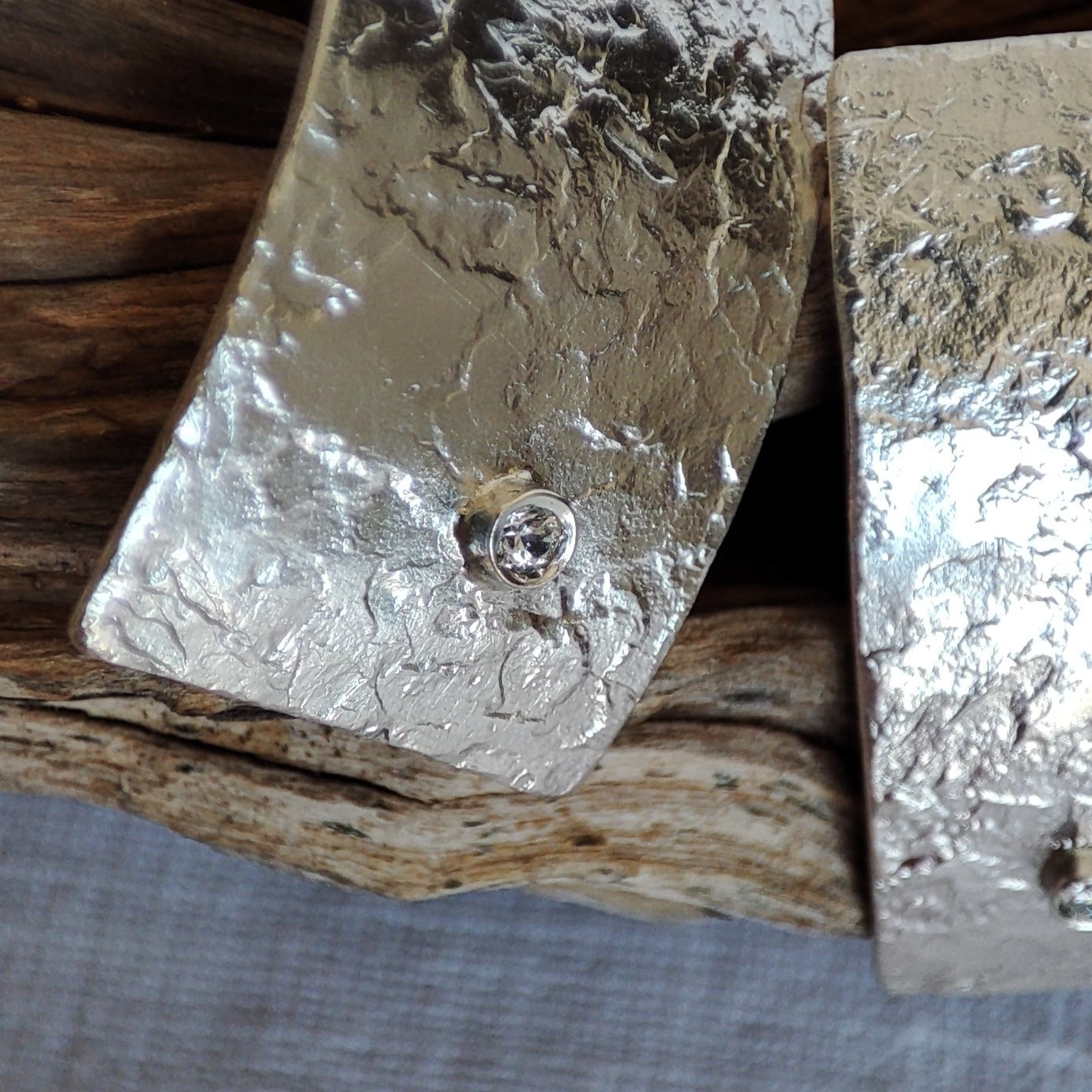 Detail of handmade, rectangular silver earrings with zircons