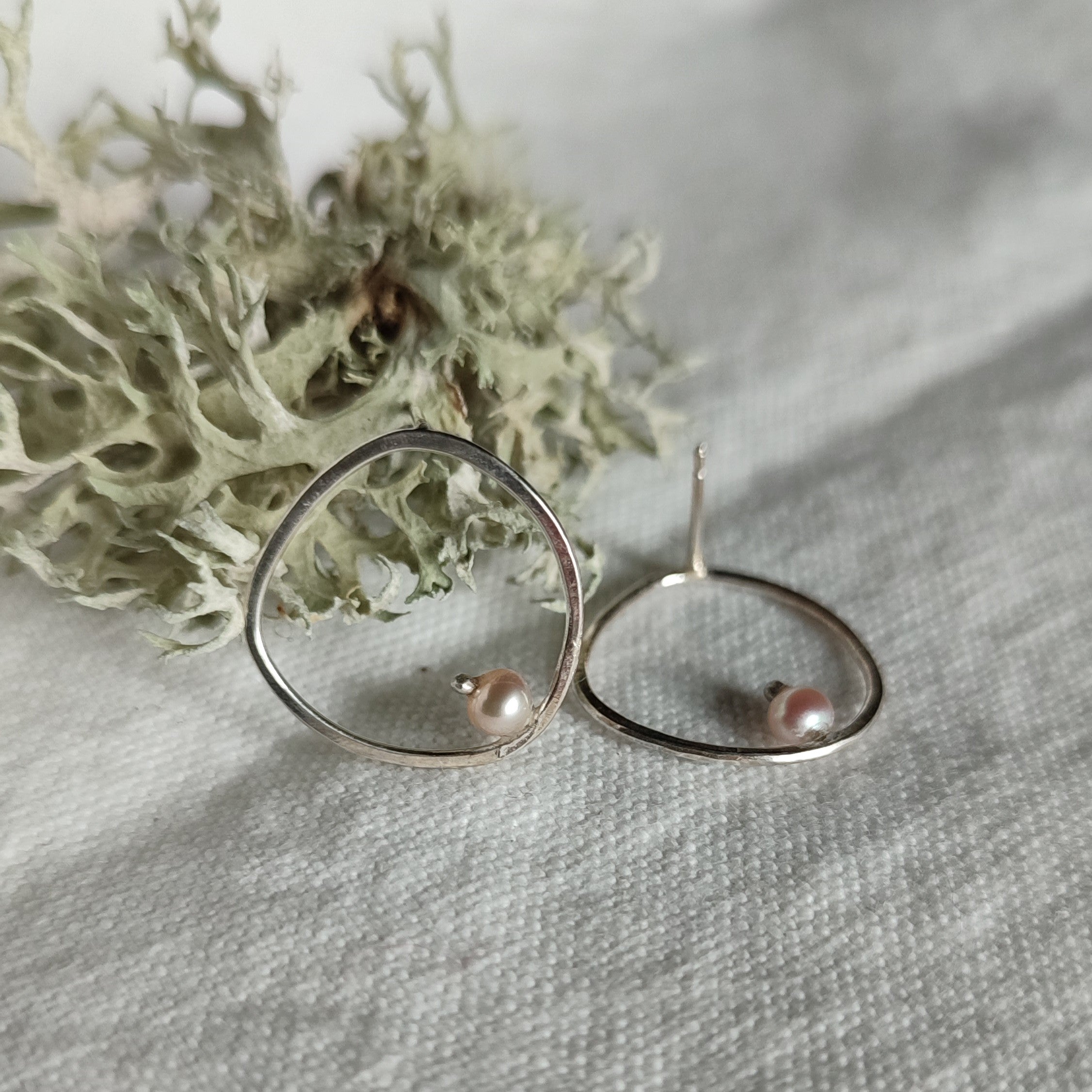 A pair of handcrafted silver earrings with pearls