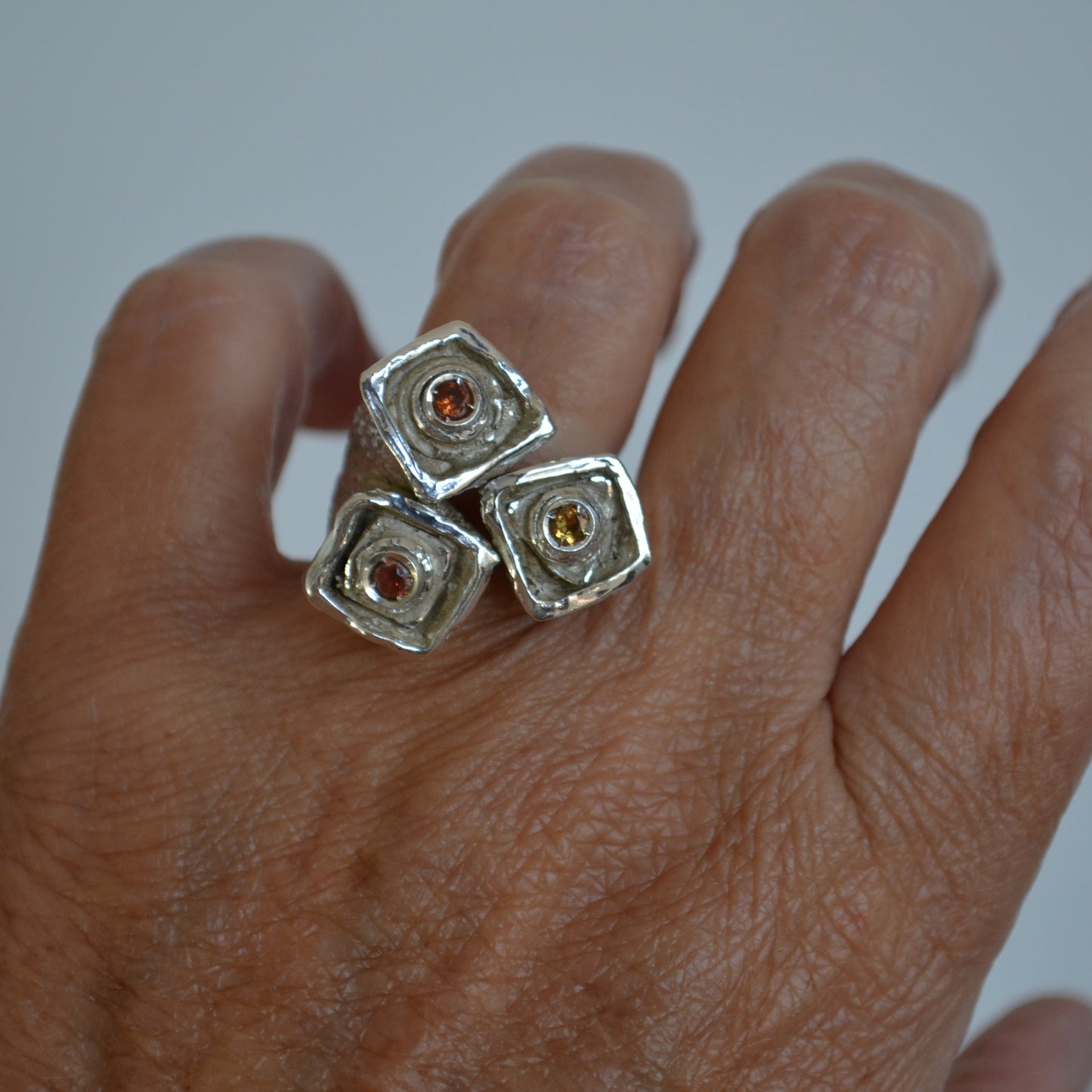 Hand with recycled silver ring with orange-yellow sapphires