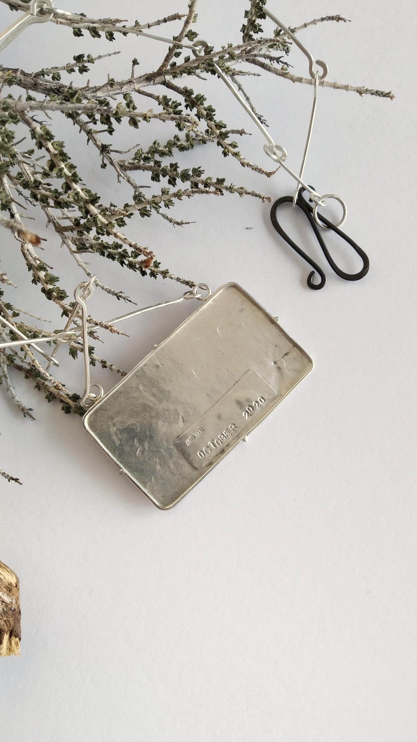 Back of a silver pendant with imprint "October 2020". Silver handmade chain and oxidized silver clasp