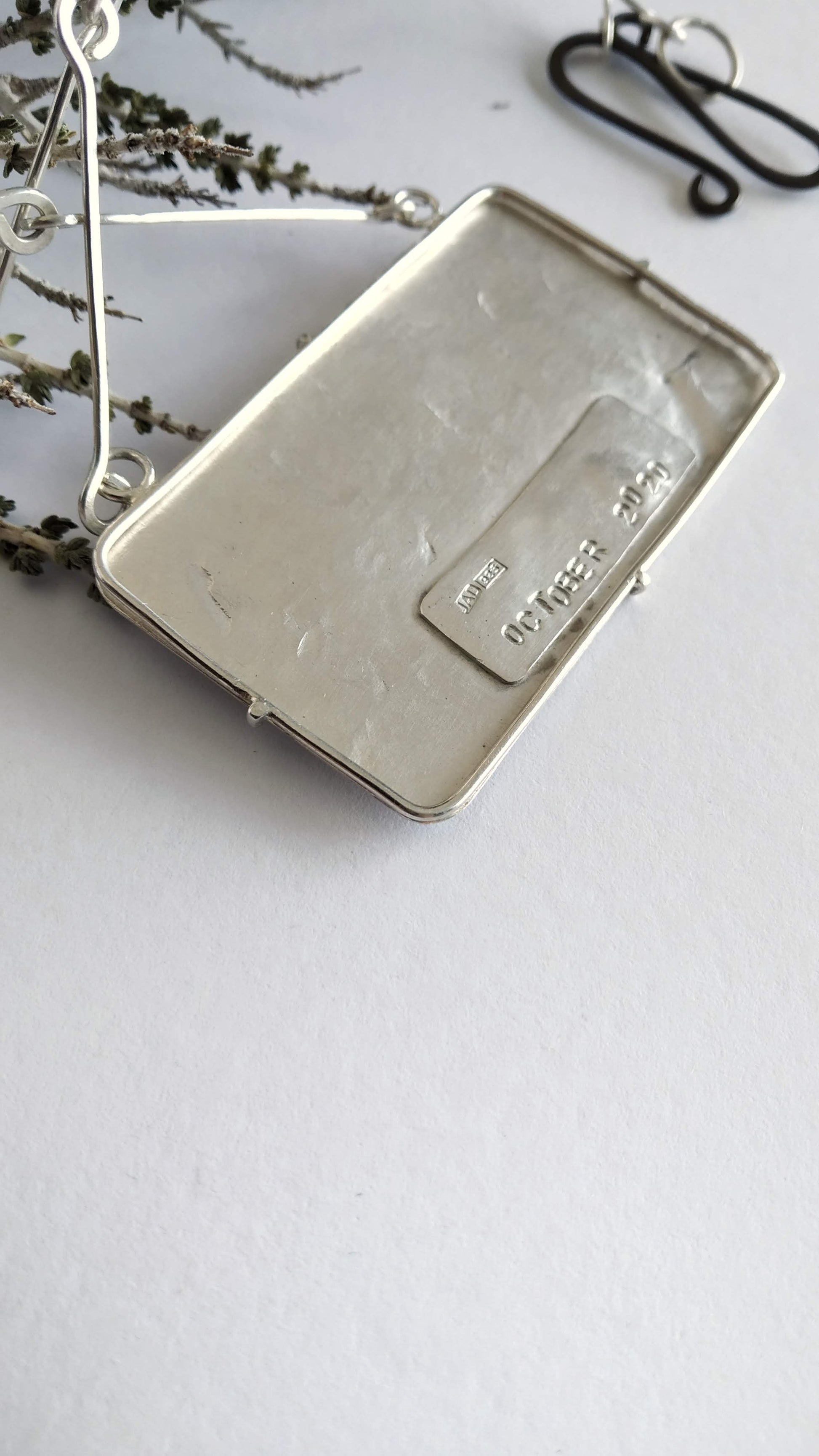 Back of a silver pendant with imprint "October 2020". Silver handmade chain and oxidized silver clasp