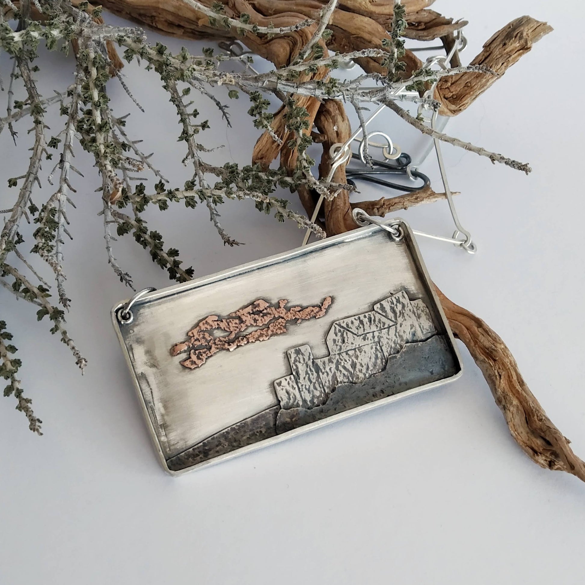Silver pendant with oxidized silver and copper layers representing a village in Italy