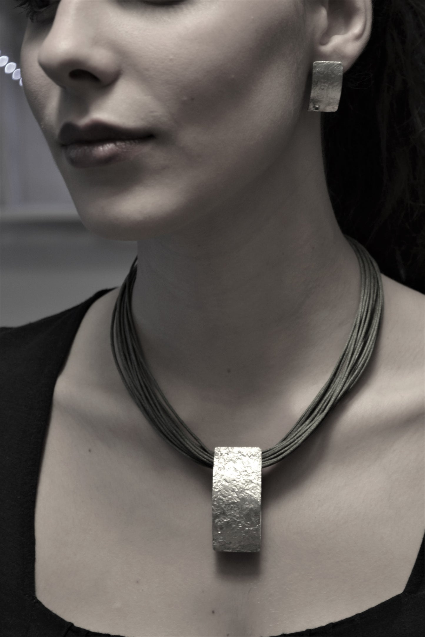 Model wearing a handmade silver pendant with irregular surface and earrings